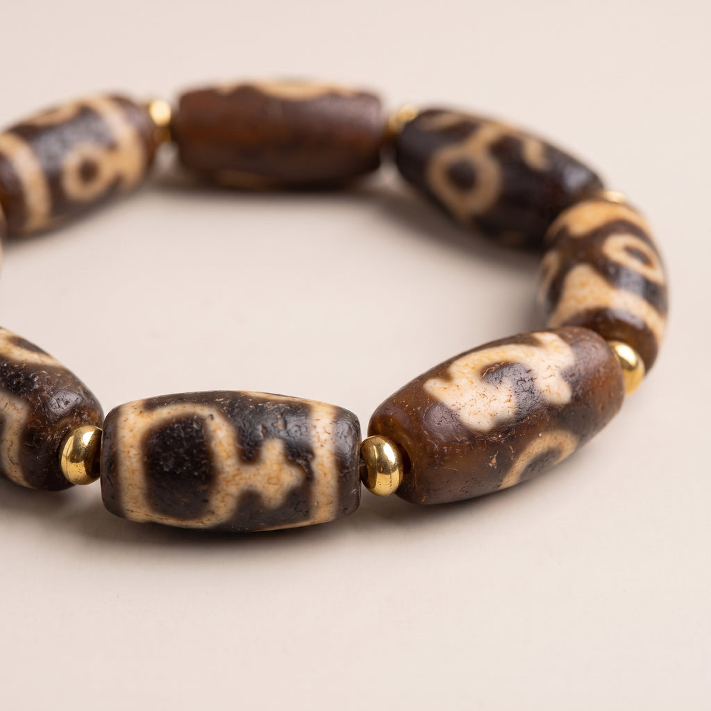 Macro close-up of multiple weathered old dzi beads showing the natural surface texture and traditional pattern details.