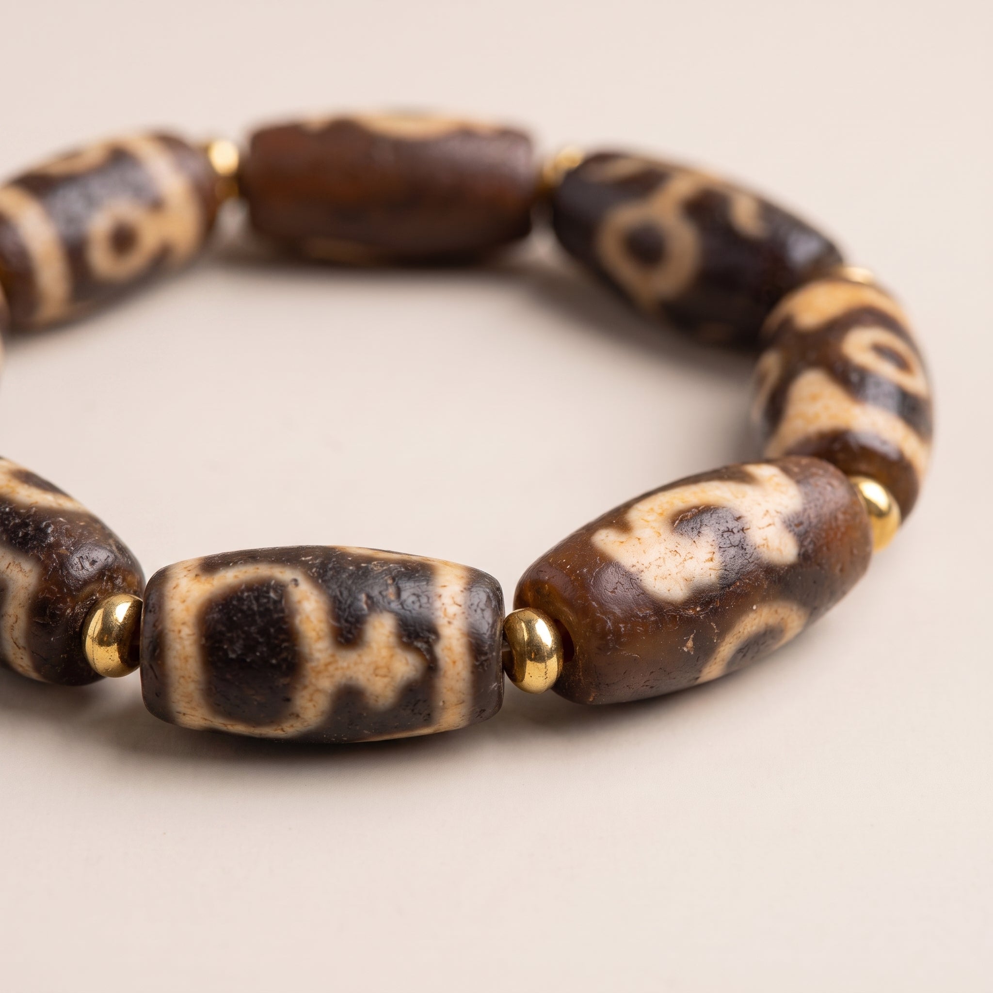 Macro close-up of multiple weathered old dzi beads showing the natural surface texture and traditional pattern details.