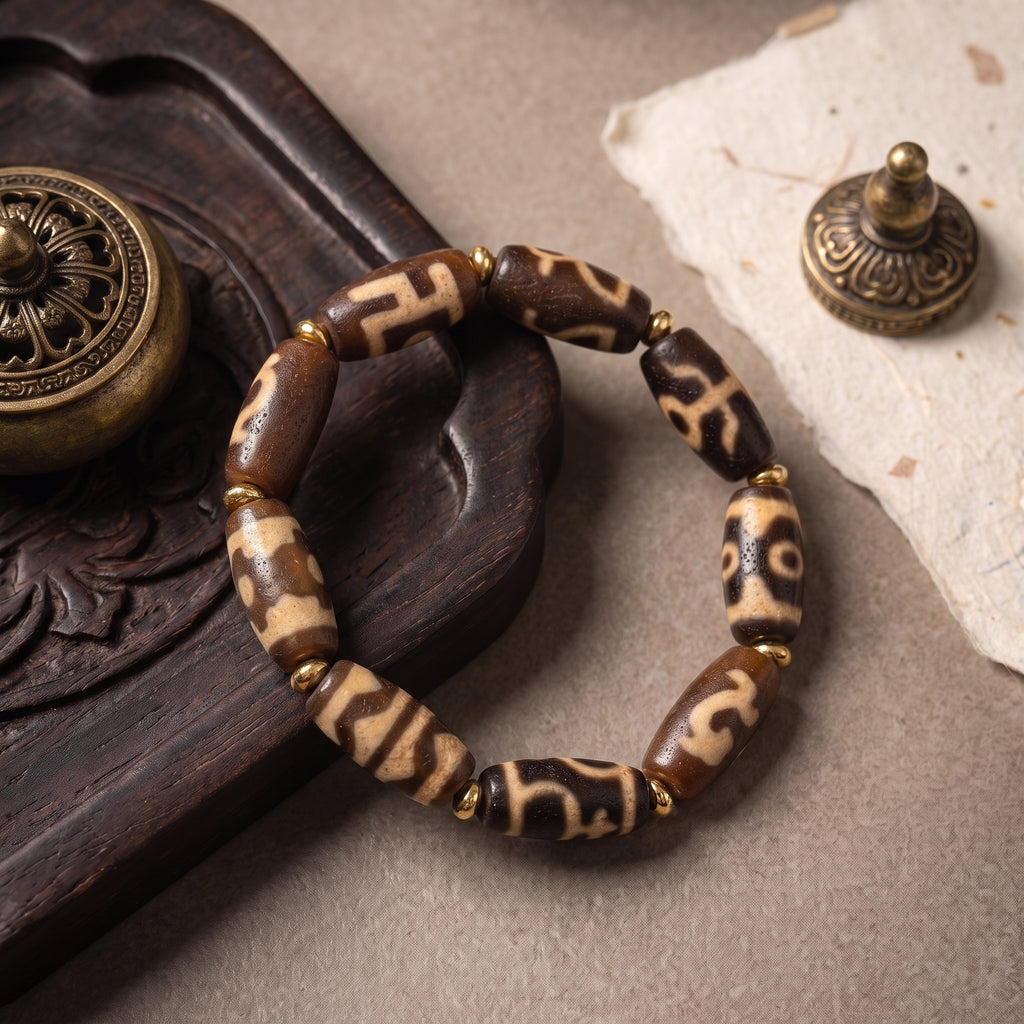 Weathered old dzi bead bracelet styled on a carved dark wood tray with antique-inspired props.