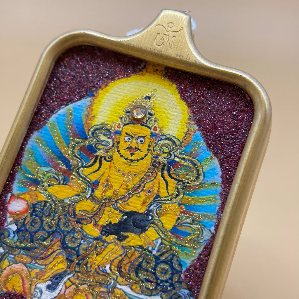 六字真言圓形手繪描金佛牌背面圖，展示金色背面浮雕法器圖案、圓形邊框紋飾及金屬質感